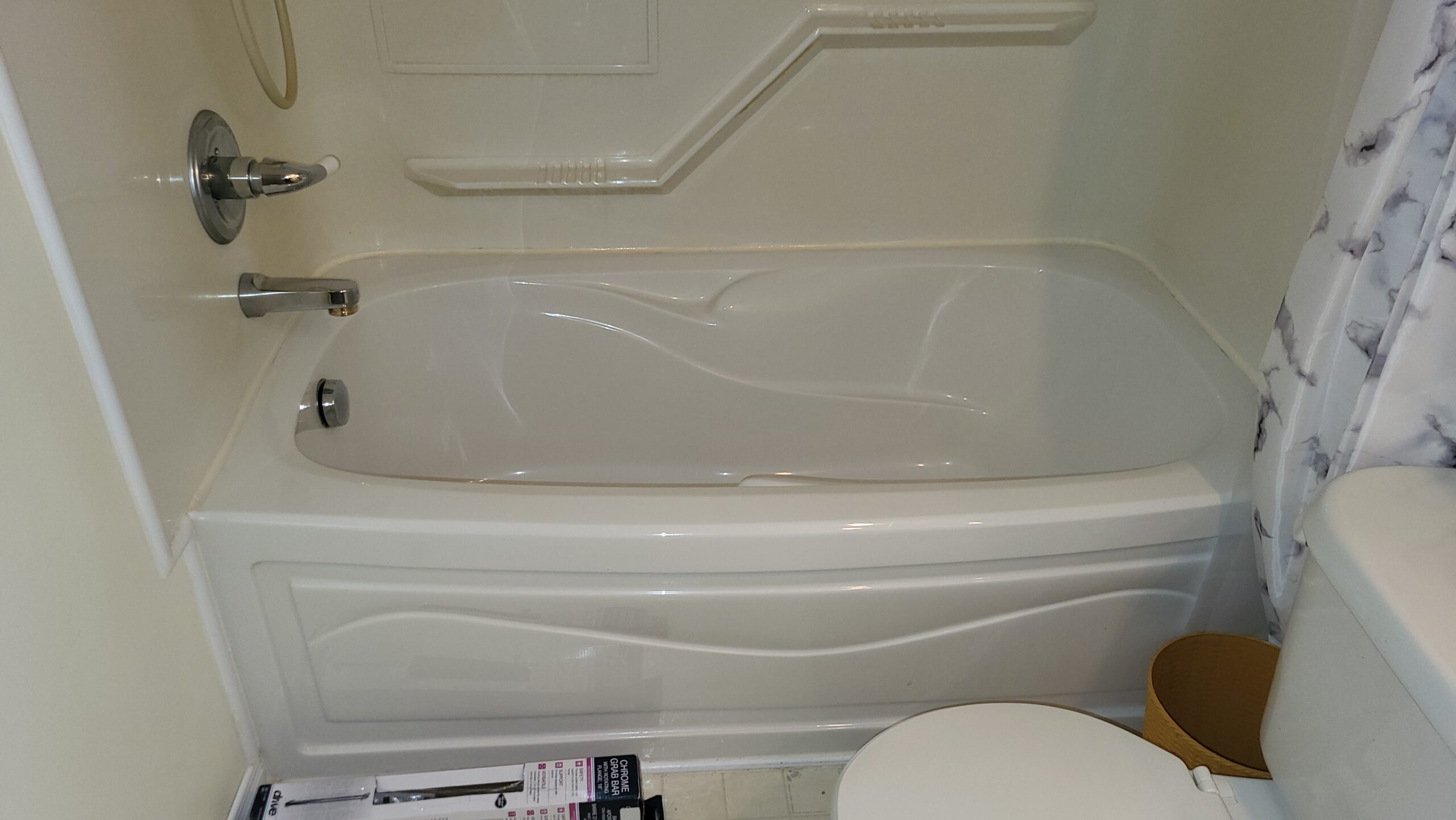 Standard bathtub with smooth fiberglass enclosure and chrome fixtures