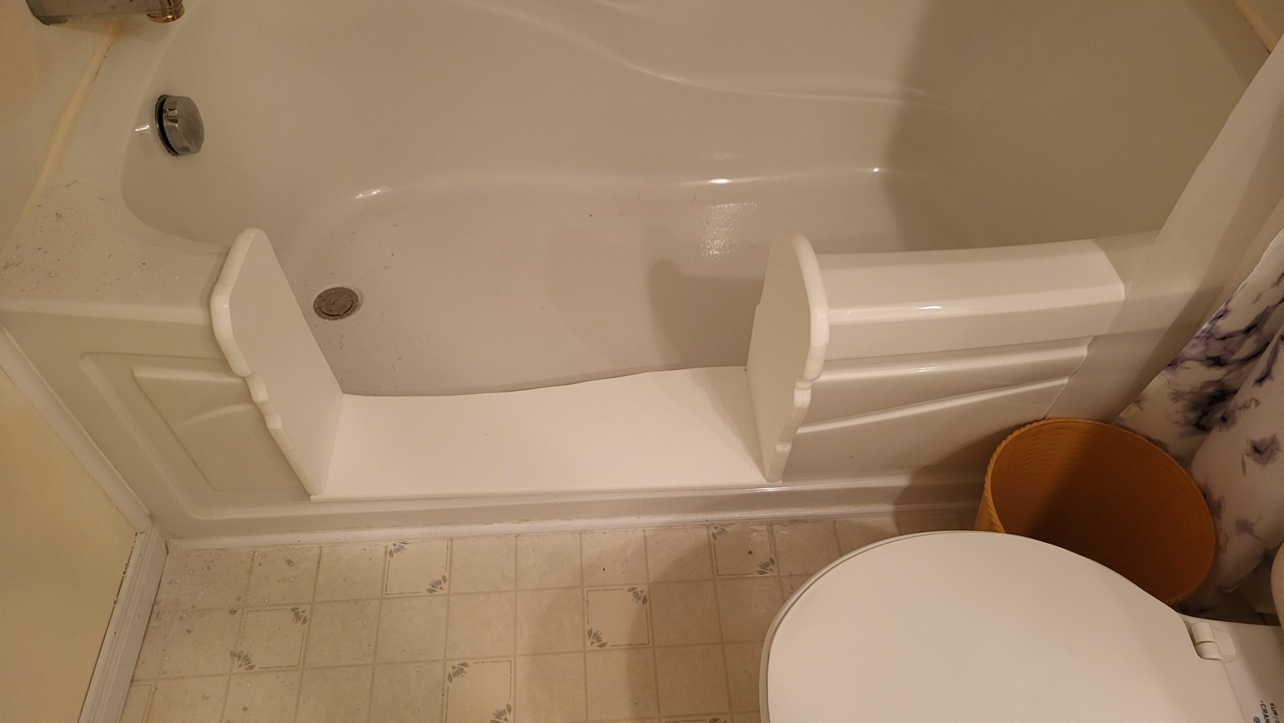 White bathtub with step-through insert for safer access