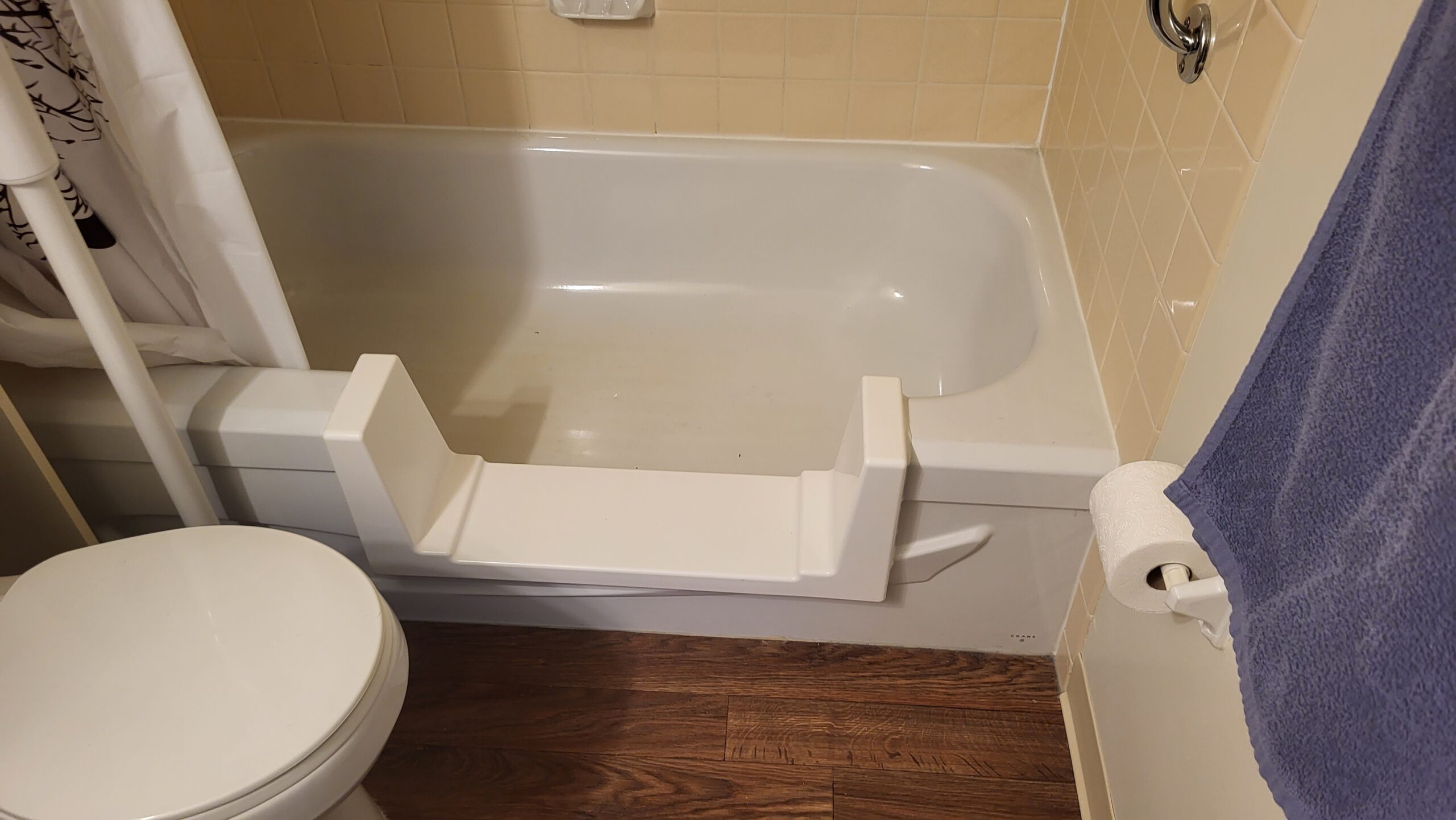 Bathtub with side access insert and beige tile wall in compact bathroom layout