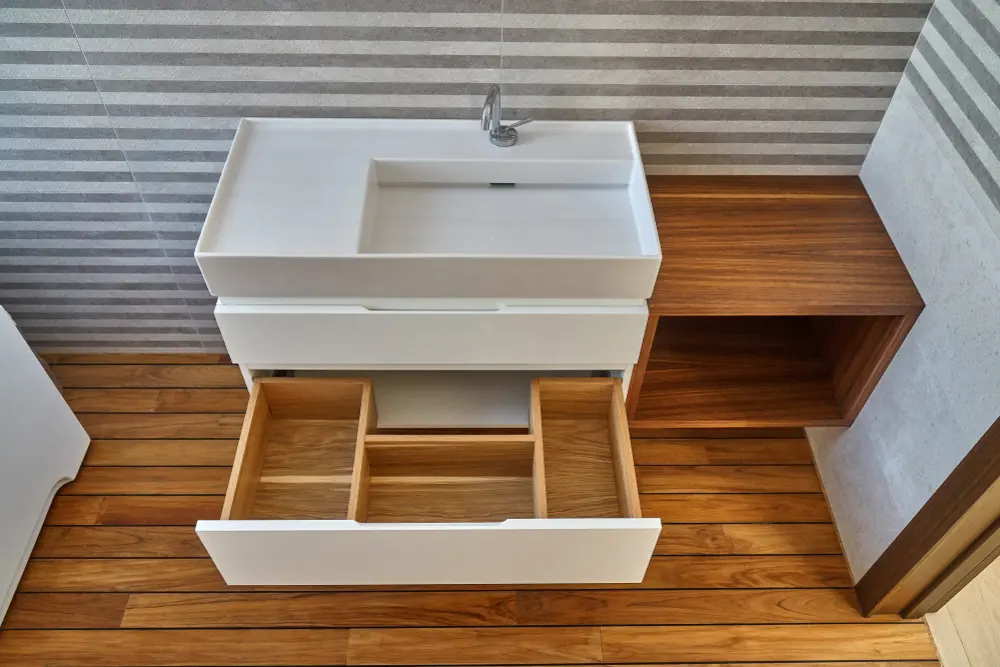 Modern white bathroom vanity with open drawers and adjacent wood shelving