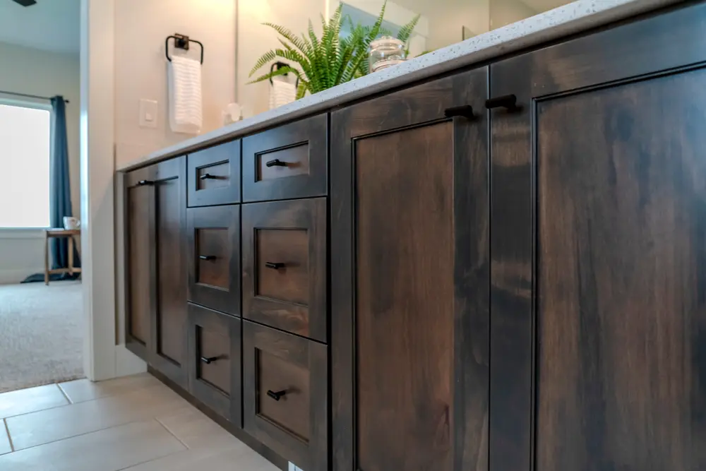 Dark wood bathroom vanity with matte black hardware and quartz countertop