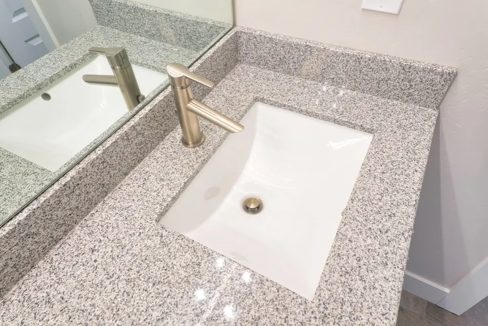 Granite bathroom vanity with rectangular undermount sink and brushed nickel faucet