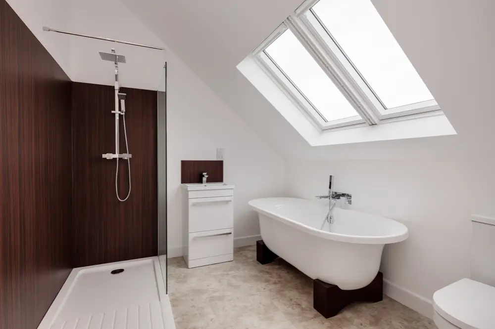 Attic bathroom with freestanding tub, wood-accented shower, and skylight windows