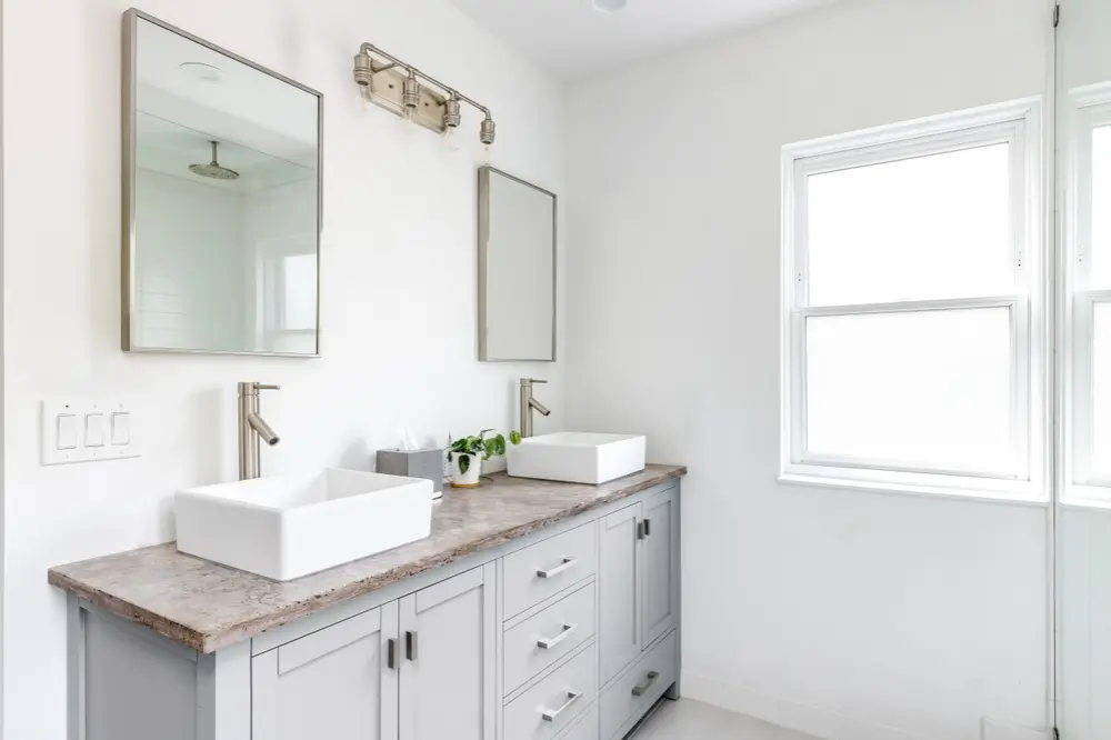 Bright bathroom with double vanity, vessel sinks, and brushed nickel faucets