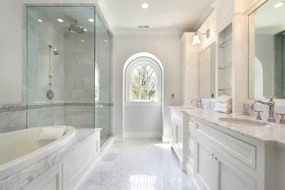 Luxurious white marble bathroom with freestanding tub, glass-enclosed shower, and double vanity