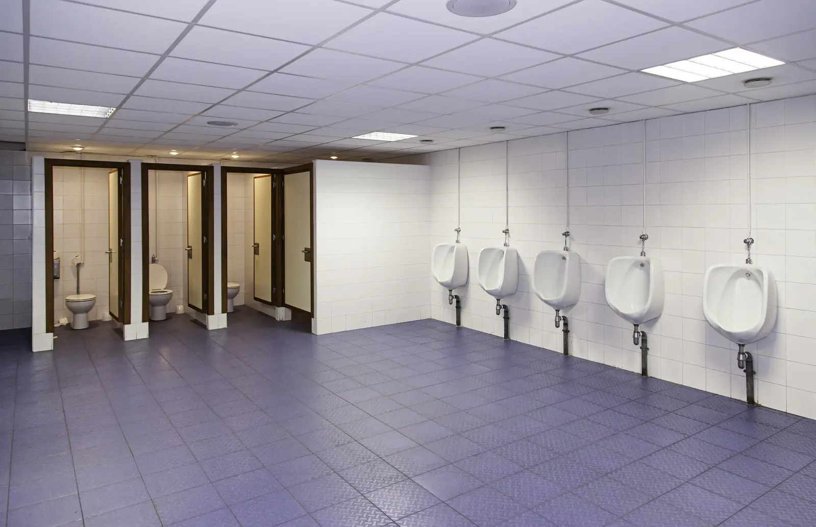 Public men’s restroom with toilet stalls and wall-mounted urinals