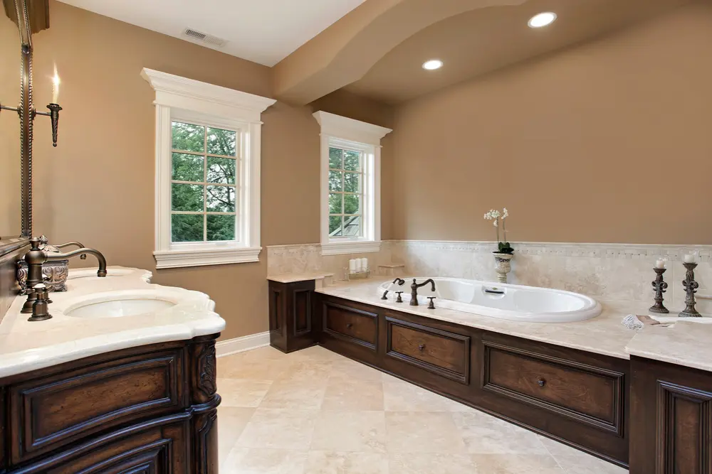 Traditional bathroom with built-in bathtub, wood cabinetry, and beige walls