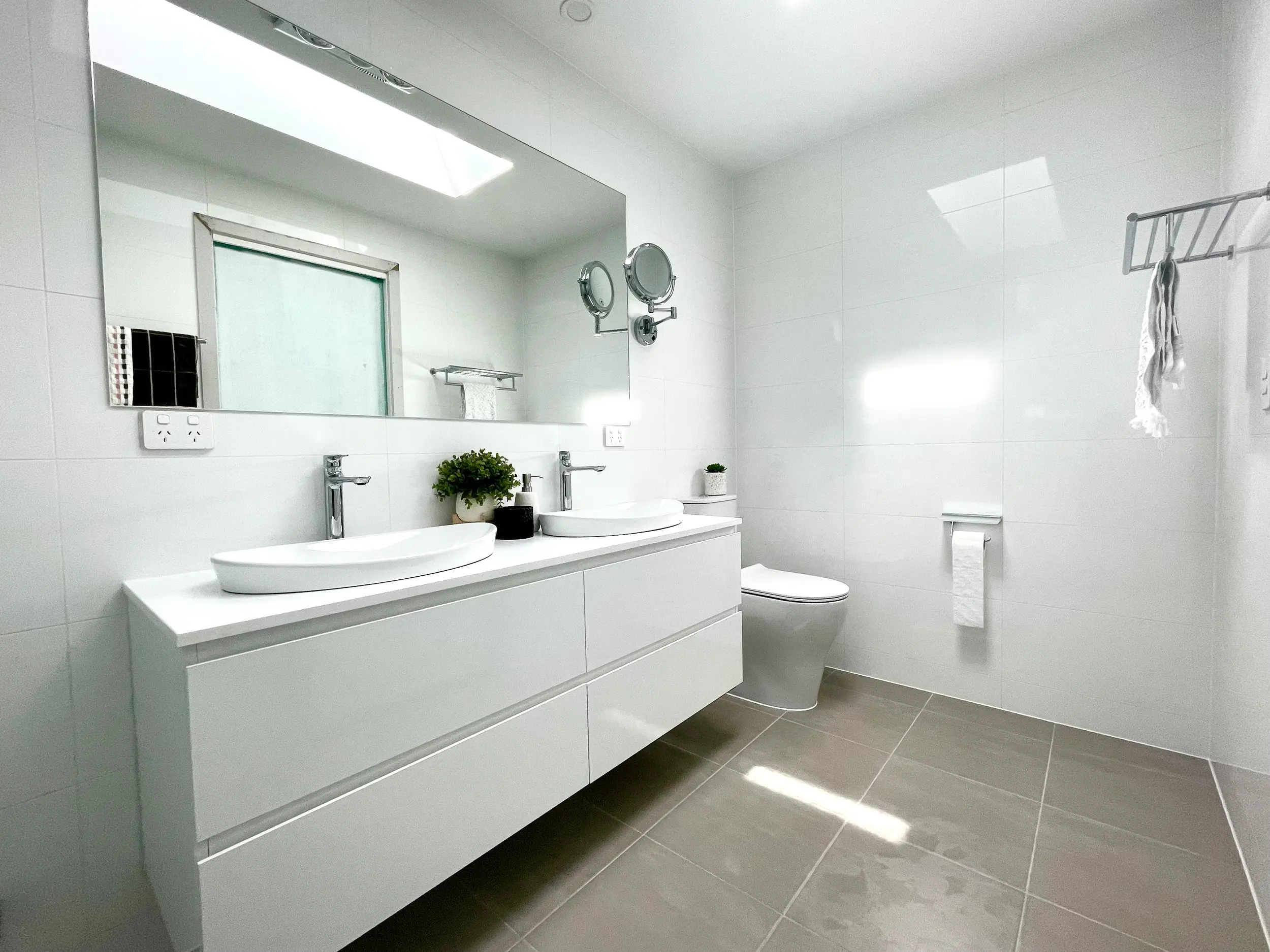 Minimalist white bathroom with double vanity and large mirror