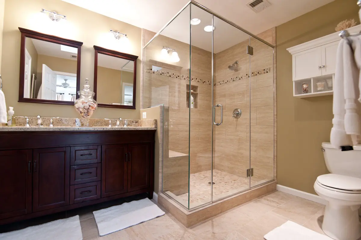 Bathroom with glass-enclosed shower, double vanity, and beige walls