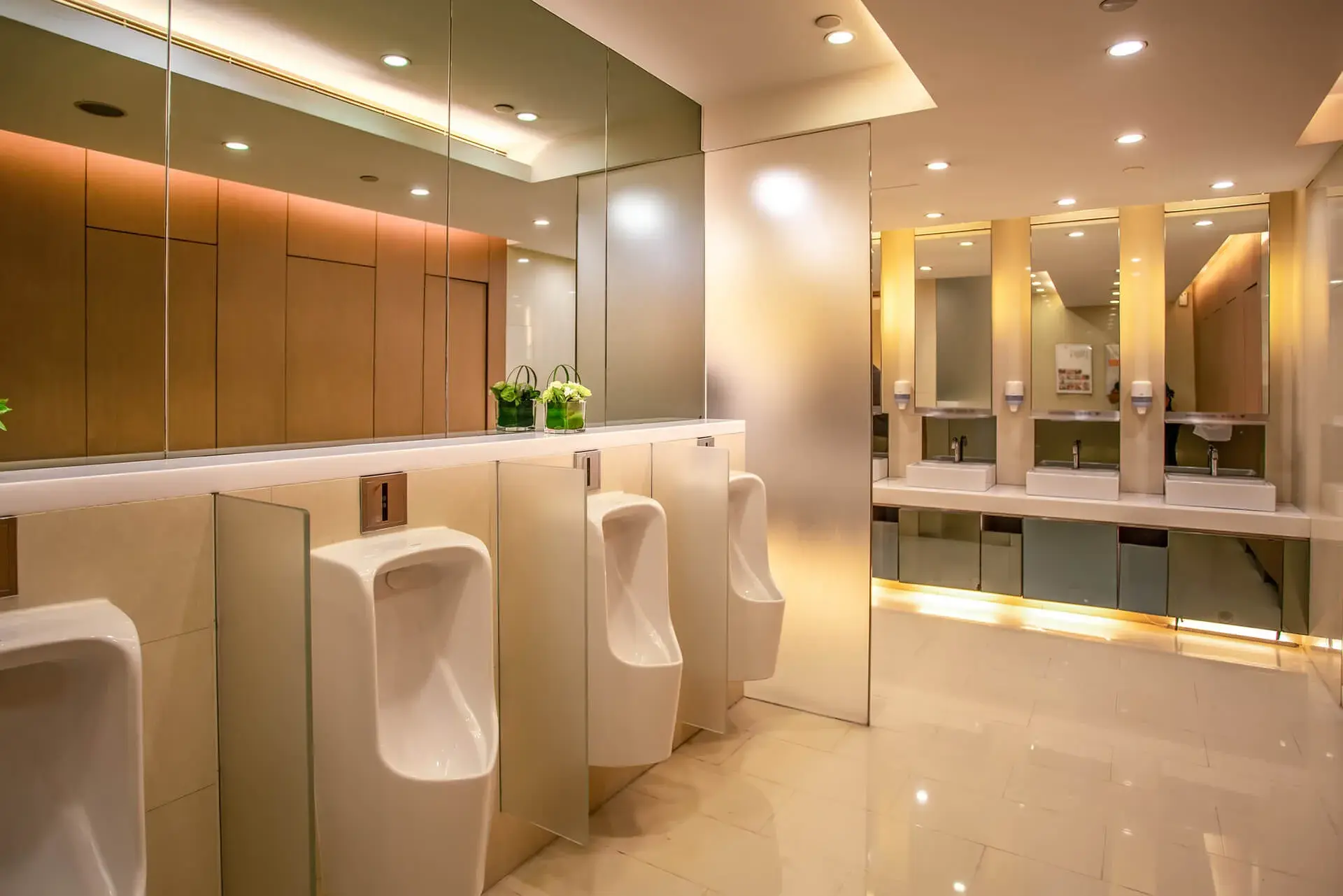 Luxurious men's restroom with urinals, sinks, mirrors, and warm lighting