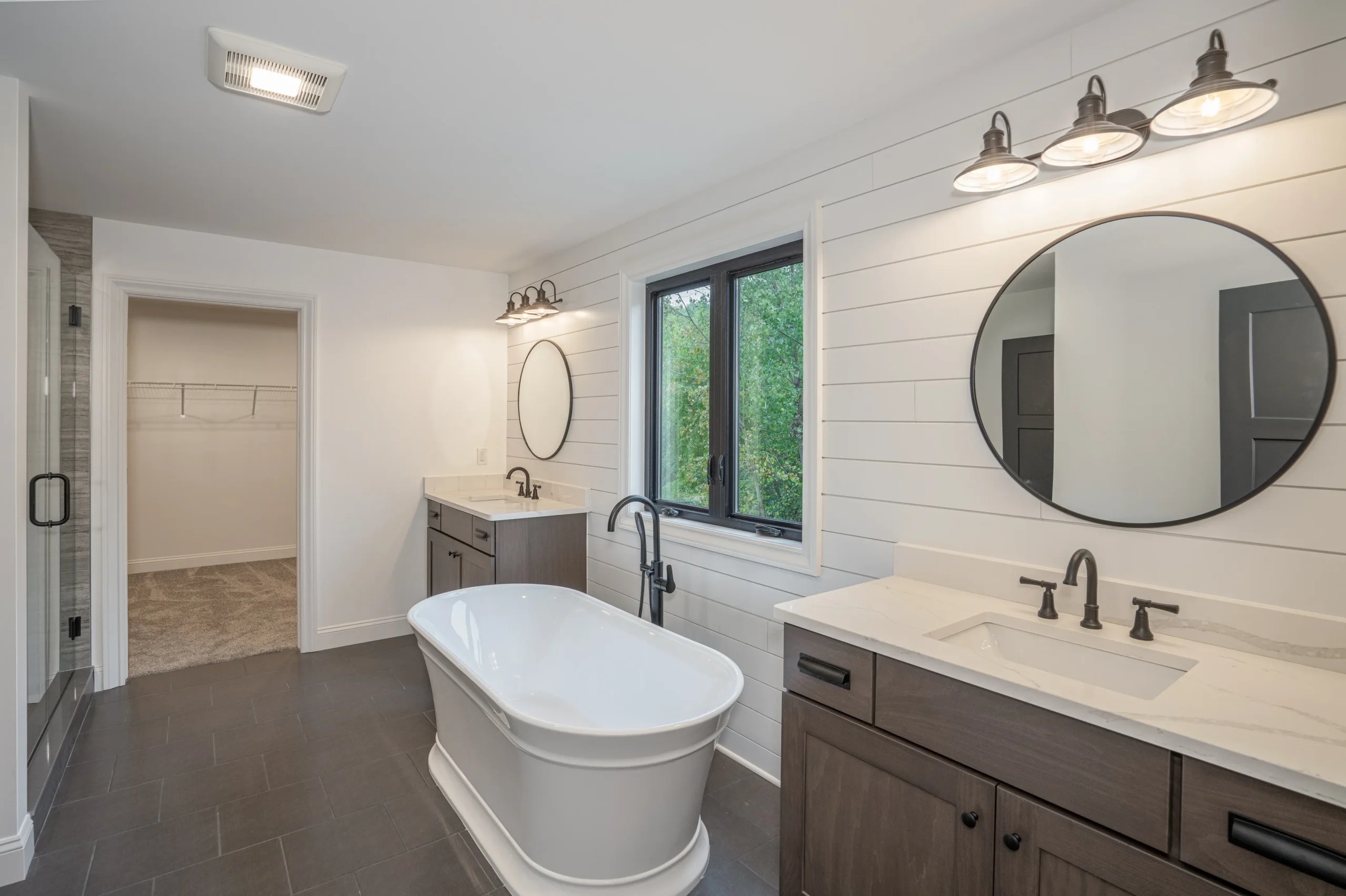 Modern farmhouse bathroom with freestanding tub, dual vanities, and shiplap walls